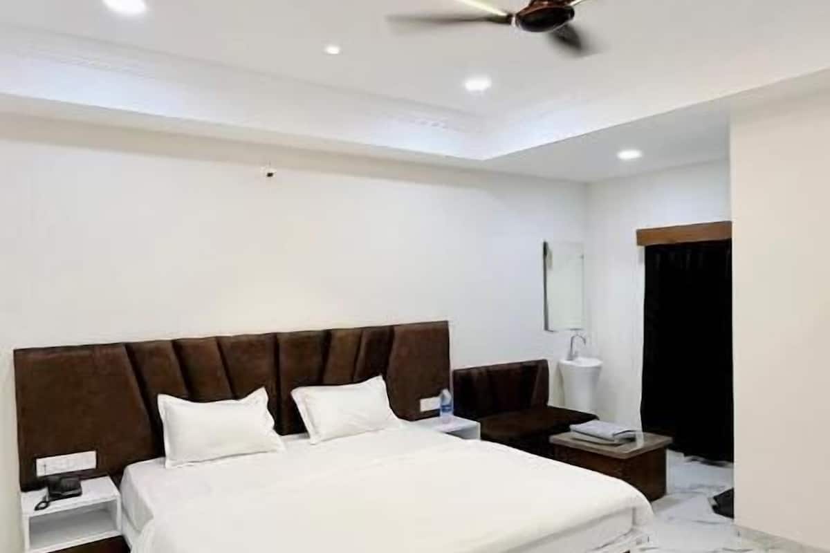 Um quarto moderno com uma cama, mesas de cabeceira, um ventilador de teto e piso de mármore.