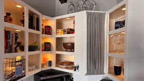 A kitchen with white cabinets, a microwave, a coffee maker, and a bicycle mounted on the wall.