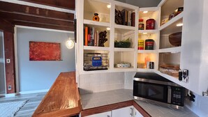 A kitchen with white cabinets, a microwave, and a wooden countertop.