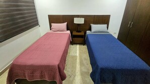 Una camera da letto con due letti, un comodino, una lampada, un armadio e una finestra con persiane.
