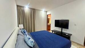 Una camera da letto con un letto, tende, una TV e una scrivania.
