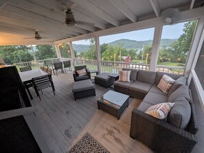 A covered outdoor deck with seating, a table, and a view of a green landscape. - Nolin Paradise Found- Direct Water/Dock Access! (Mammoth Cave)