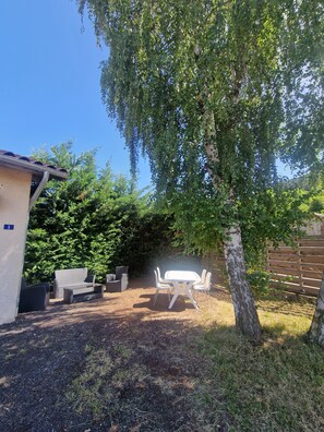 A patio area with outdoor furniture, a tree, and a building with a number sign. - A single-story house with a warm and welcoming atmosphere, located in the heart of the village (Lantriac)