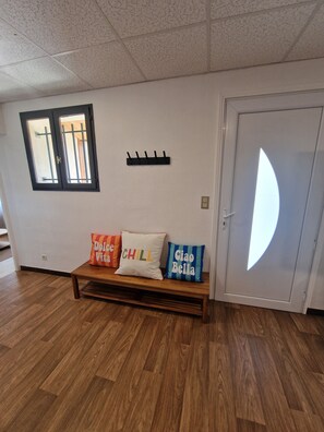 A room with a wooden bench, a wall-mounted coat rack, a door with a semi-circular glass panel, and a window with metal bars. - A single-story house with a warm and welcoming atmosphere, located in the heart of the village (Lantriac)