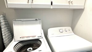 A laundry area with two washing machines and a dryer, a ventilation unit, and white cabinets above. - Home in Panama City - Seahorse Oasis (Panama City)