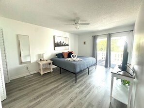 A bedroom with a bed, a nightstand, a ceiling fan, a window with curtains, and a television on a stand. - Home in Panama City - Seahorse Oasis (Panama City)