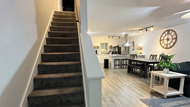 A staircase leading to a living area with a dining table, chairs, a clock, and a plant. - Home in Panama City - Seahorse Oasis (Panama City)