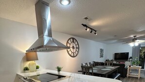 A modern kitchen with a central island, built-in oven, and stainless steel range hood. - Home in Panama City - Seahorse Oasis (Panama City)