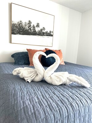 A bed with a blue quilt, two pillows, and a towel arranged in a heart shape. - Home in Panama City - Seahorse Oasis (Panama City)