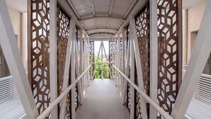 A covered pedestrian walkway with a geometric pattern on the sides and a metal railing. - Corporate Stays CorAr 1L (Asunción)