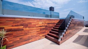 A modern building with a wooden facade, glass upper levels, and a staircase. - Corporate Stays CorAr 1L (Asunción)
