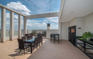 Kattoterassi, jossa on ruokailualue, ulkotiloihin sijoitettuja istuimia ja televisio.