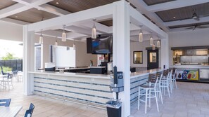 A modern outdoor bar area with a counter, seating, and a television screen. - 3BR Condo at Champions Gate Resort near Disney (Kissimmee)