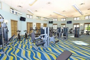 Ein Fitnessraum mit verschiedenen Trainingsgeräten, einer Bank und einem gemusterten Teppich.