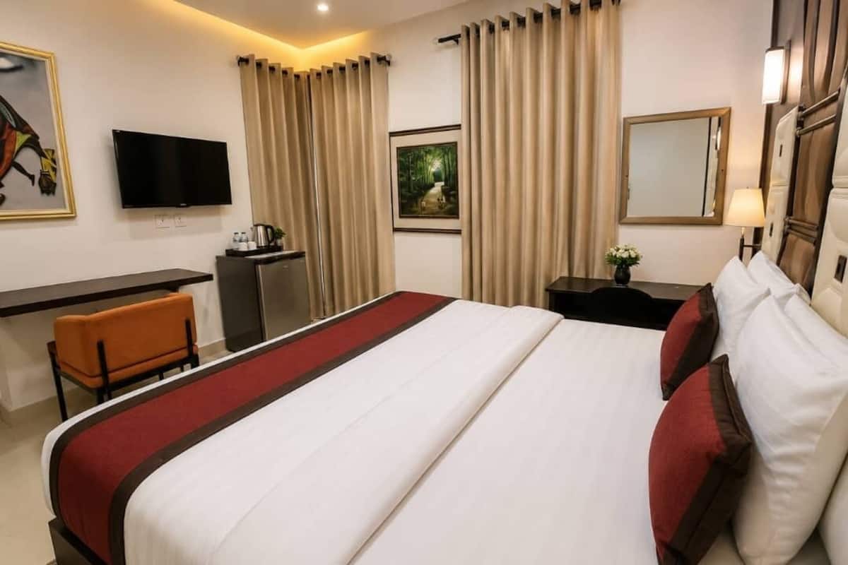 A hotel room with a bed, a desk, a chair, a television, and curtains.