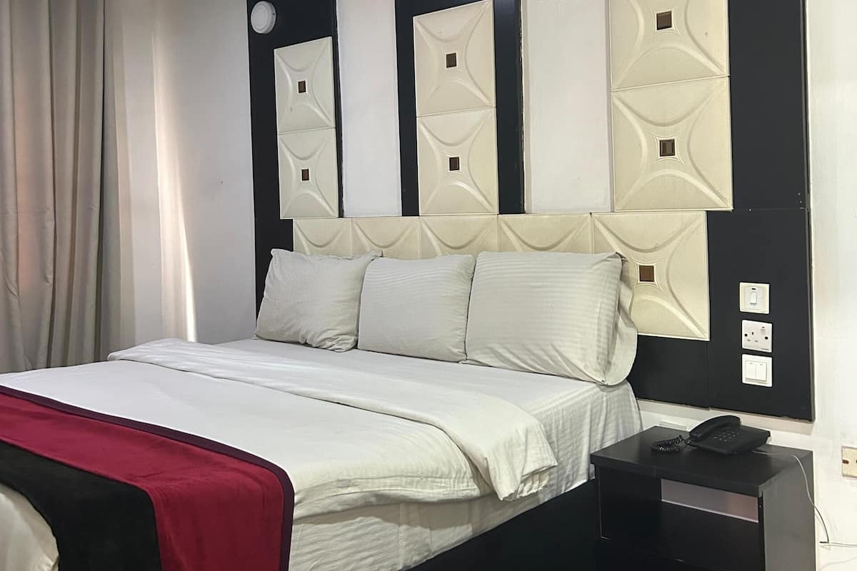 A bedroom with a bed, a nightstand, a telephone, and a ceiling fan.