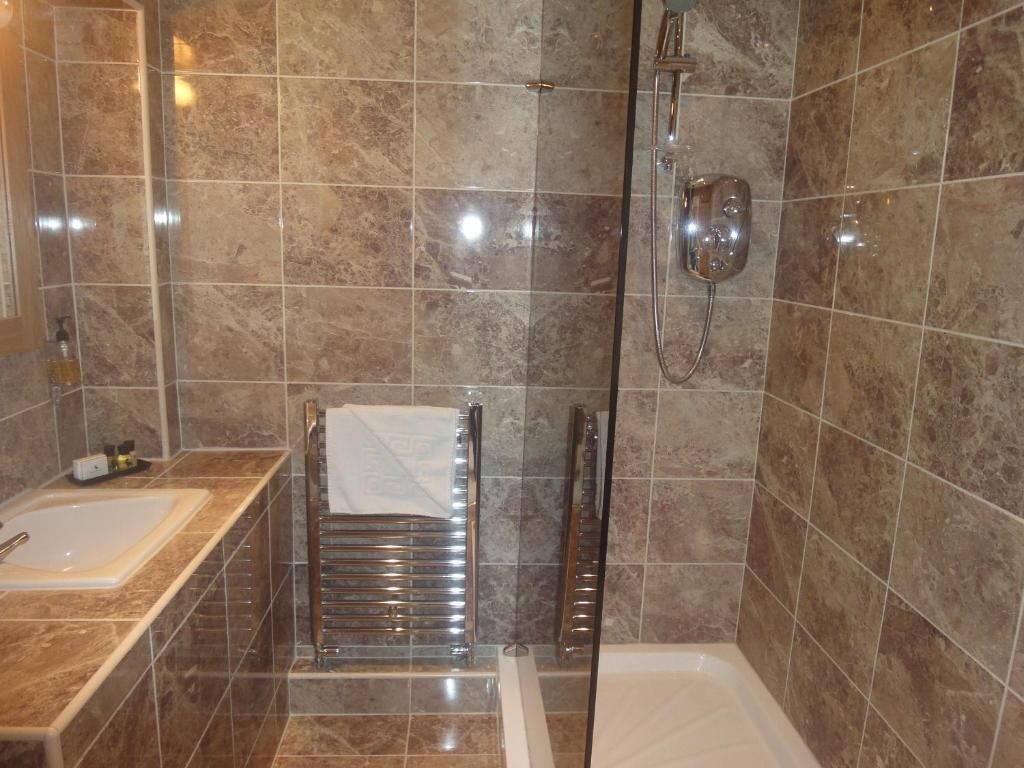 A bathroom with a bathtub, a shower, and a towel rack.