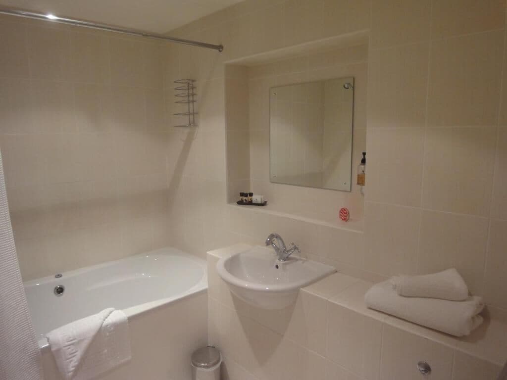Een badkamer met een bad, wastafel en spiegel.