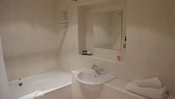 Een badkamer met een bad, wastafel en spiegel.