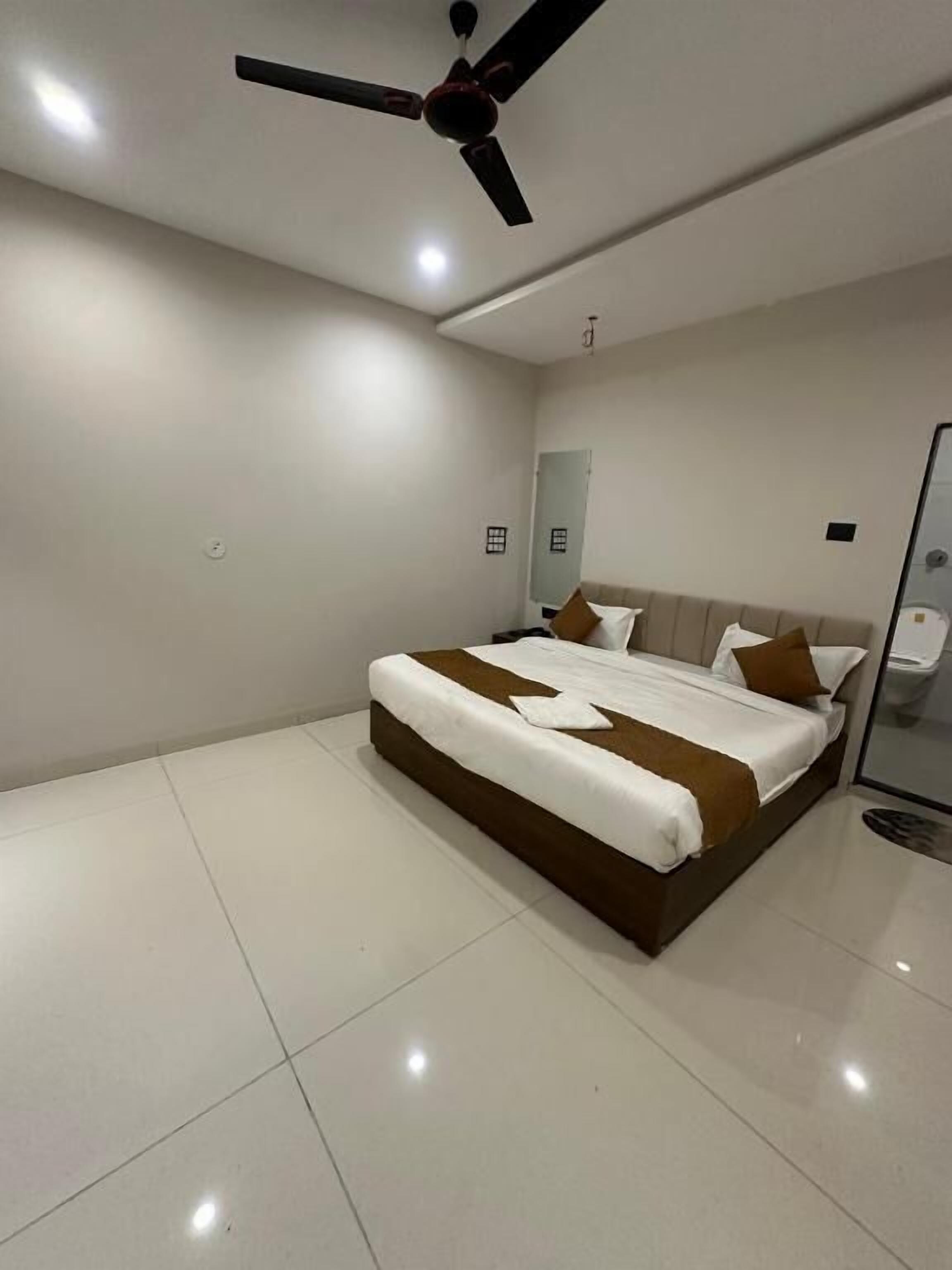 A bedroom with a bed, a ceiling fan, and a mirror.
