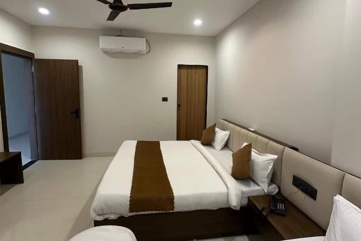 Quarto de hotel com cama, ventoinha no teto, aparelho de ar condicionado e mesa de cabeceira.