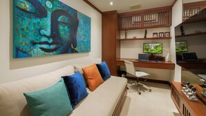 A modern living room with a large abstract painting, a sofa with colorful cushions, a desk with a computer, and a TV. - Residence Disa – Panoramic sea views above Patong Bay, just steps from the beach (ตำบลป่าตอง)