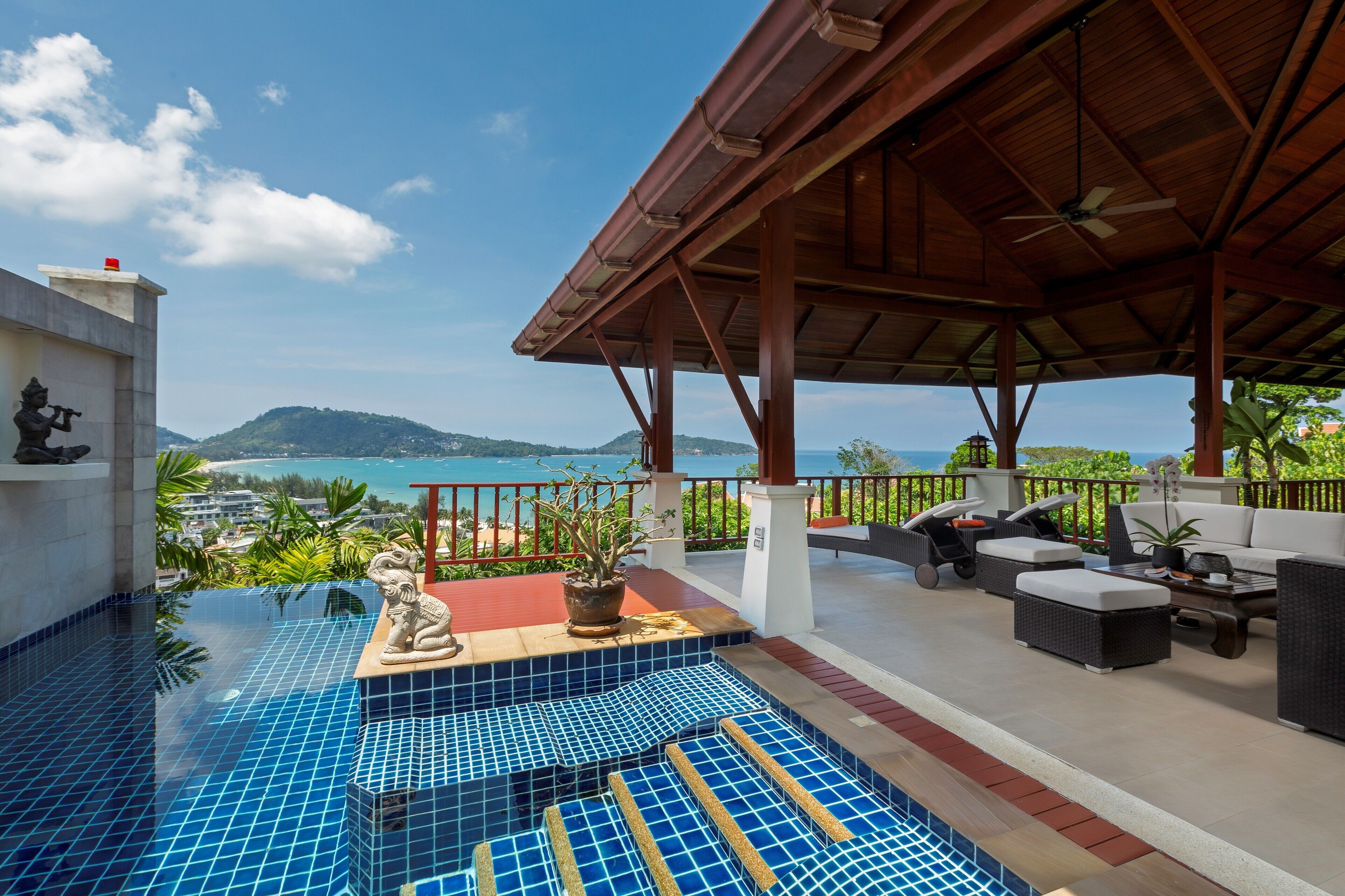 A rooftop pool area with a view of the sea, outdoor seating, and a covered patio.