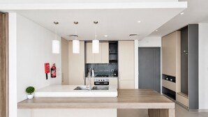 Une cuisine moderne dotée d’un îlot central, de luminaires suspendus et d’appareils électroménagers intégrés.
