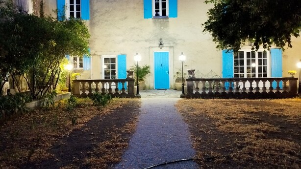 Un bâtiment doté d’une entrée centrale, d’une porte bleue et d’un chemin menant à cette entrée.