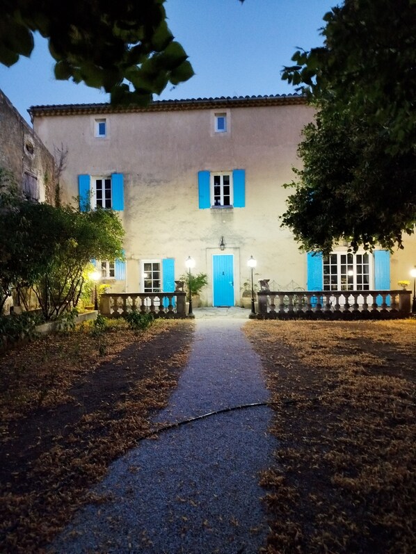 Un bâtiment doté d’une entrée centrale, d’une porte bleue et d’un chemin menant à cette entrée.