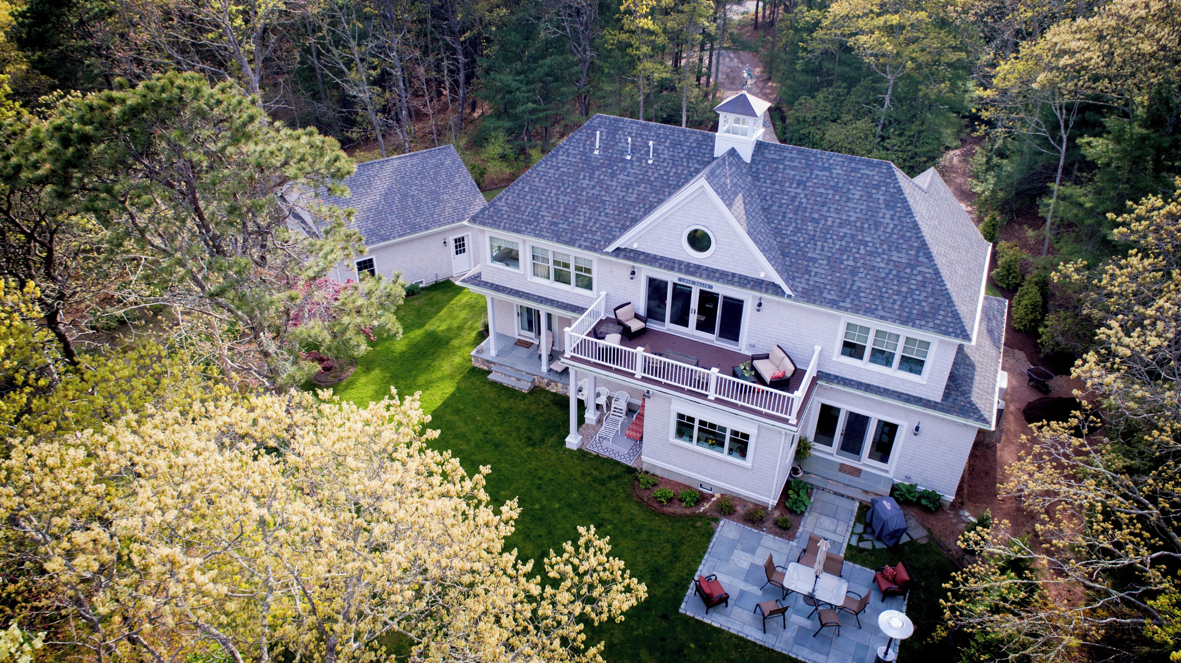 A large two-story house with a spacious deck, a covered patio, and a well-maintained lawn.