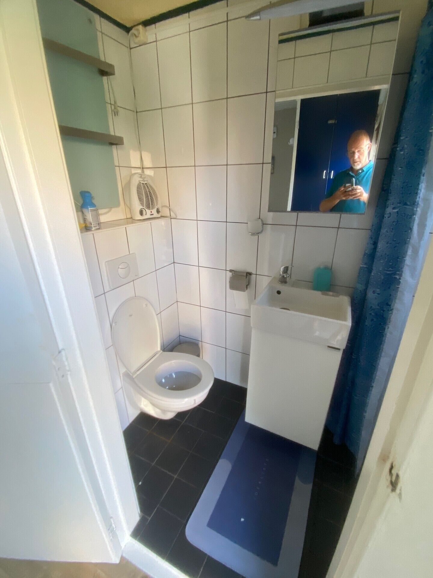 A small bathroom with a toilet, sink, and a mirror.