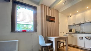 Une cuisine compacte avec un coin repas, une fenêtre avec stores, un radiateur et un four à micro-ondes.