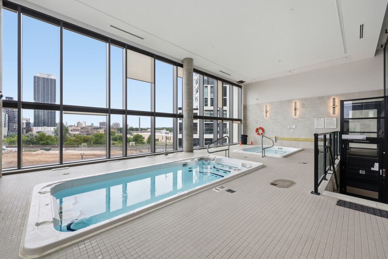 Piscina interior moderna com vista ampla para a paisagem urbana através de grandes janelas.