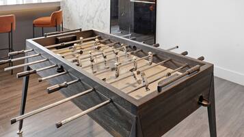 Een tafelvoetbaltafel in een moderne keuken met marmeren aanrechtbladen en een houten vloer.