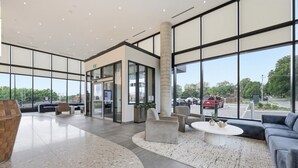 A spacious lobby with a modern design, featuring a reception desk, seating area, and large windows offering views of the parking area.