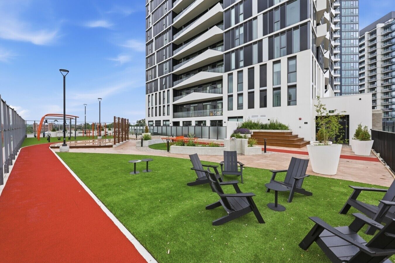 A modern building with a red pathway, outdoor seating, and a playground.