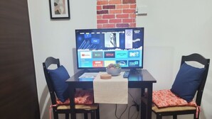 Una habitación con un escritorio, dos sillas, un televisor y una mesita con un bol.
