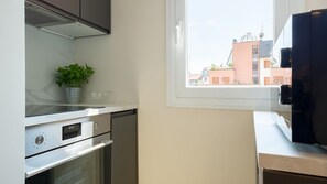 A kitchen with a stove, oven, and a window overlooking buildings. - Tabata Home (Milano)