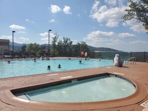 Ein Pool mit Badegästen, ein Whirlpool und Blick auf Berge.