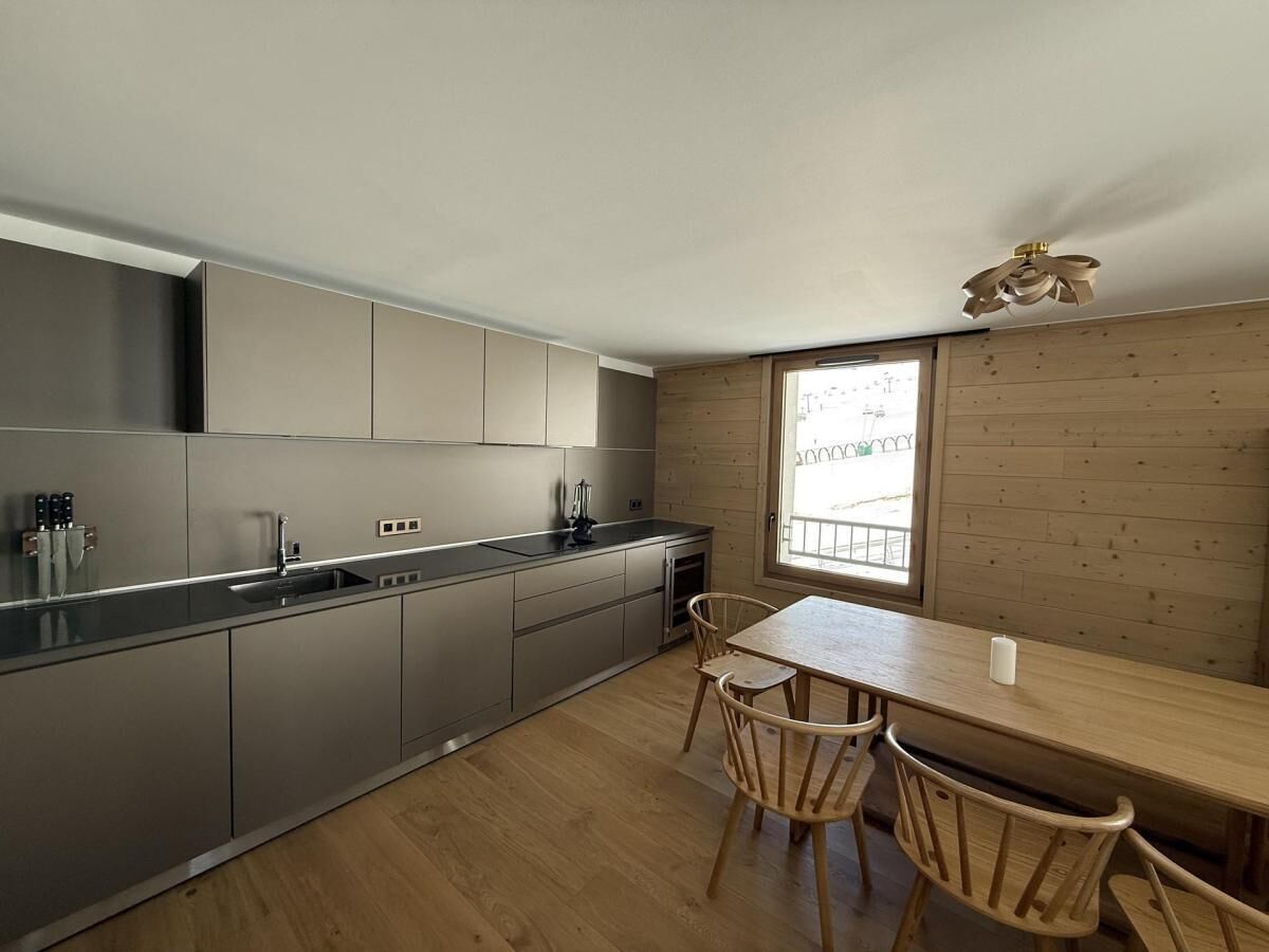 A modern kitchen with grey cabinets, a wooden dining table, and two chairs.
