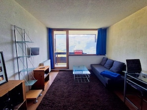 A compact living space with a sofa, a small table, a TV, and a window with curtains. - 200m from ski slopes, 7th floor, tv, 24m², Tignes (Tignes)