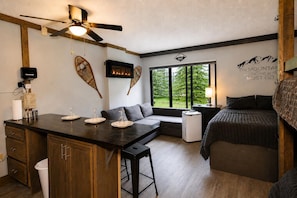 Ein gemütlicher Raum mit Küchenzeile, Essbereich, Sitzecke mit Blick und einem Bett.