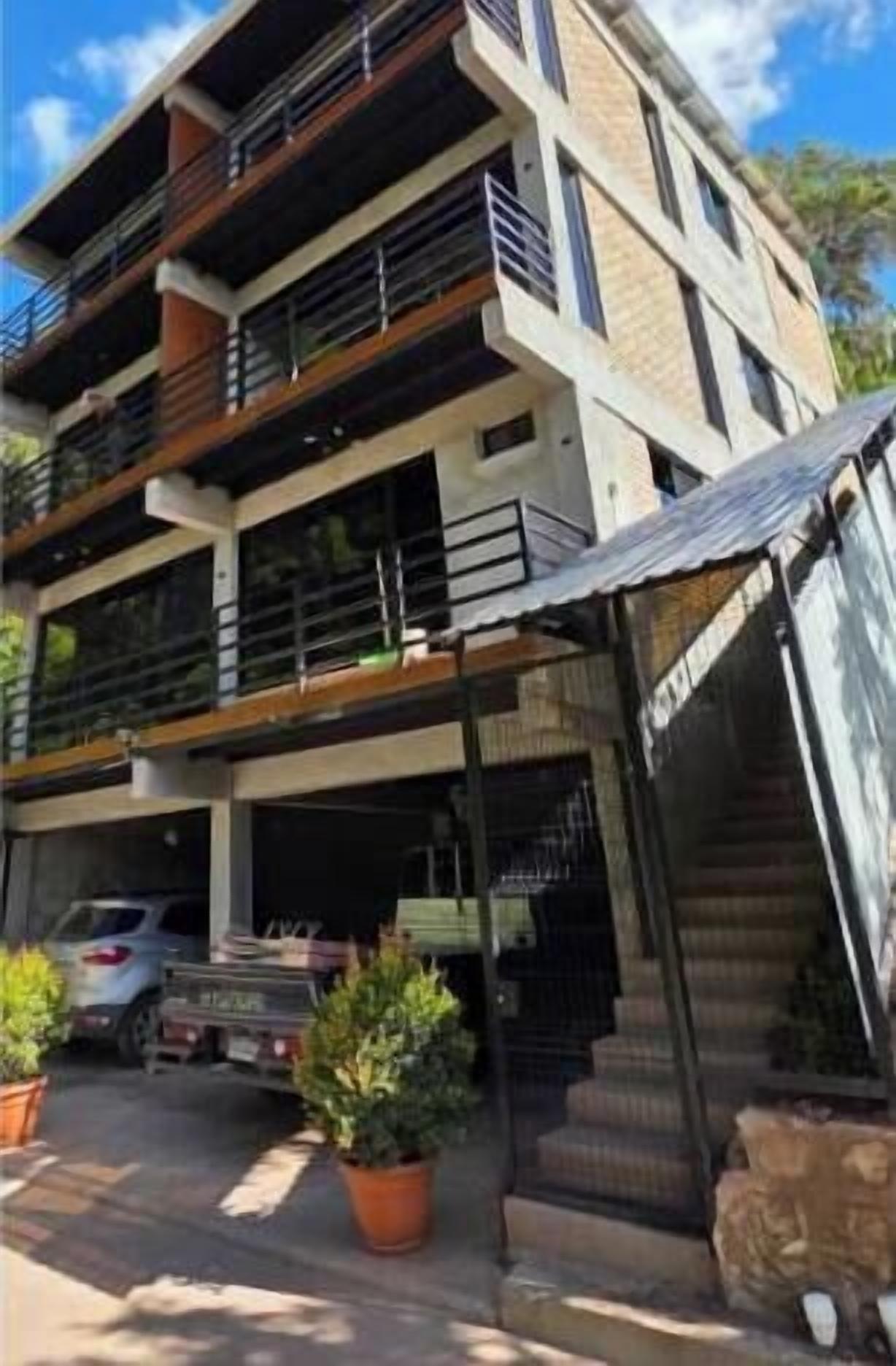 Un immeuble à plusieurs étages, doté de balcons, d’une entrée couverte et d’un escalier menant aux étages supérieurs.