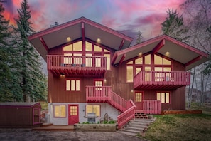 Een houten huis met twee verdiepingen, met een rode gevel, een balkon op elke verdieping en een trap naar de ingang.