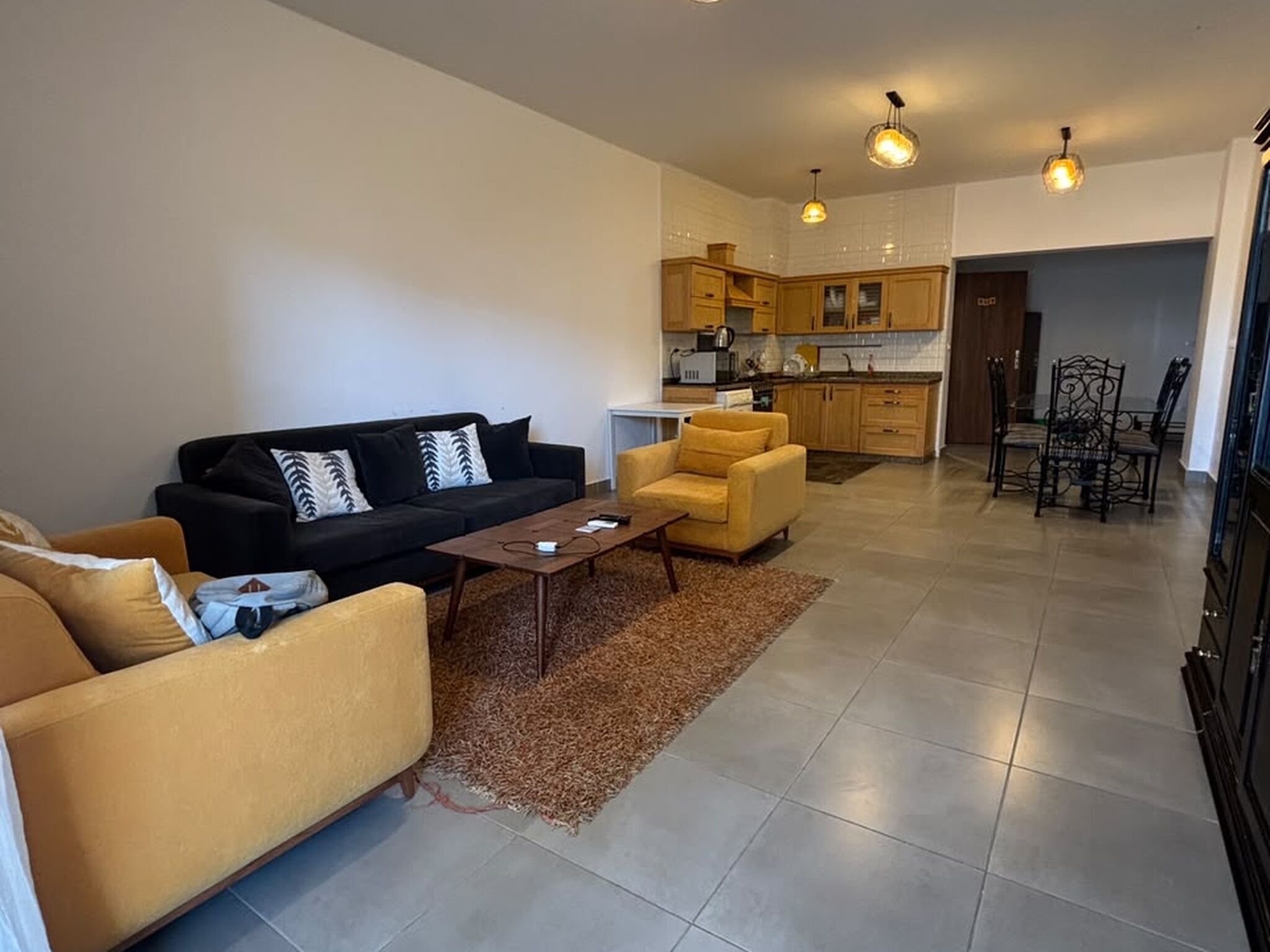 A modern living room with a sofa, armchairs, a coffee table, and a dining area with chairs.