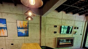 A dining area with a long table, chairs, pendant lighting, a fireplace, and artwork on the walls.