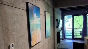 A hallway with a concrete wall, a door leading to a balcony, and a small table with a chair.