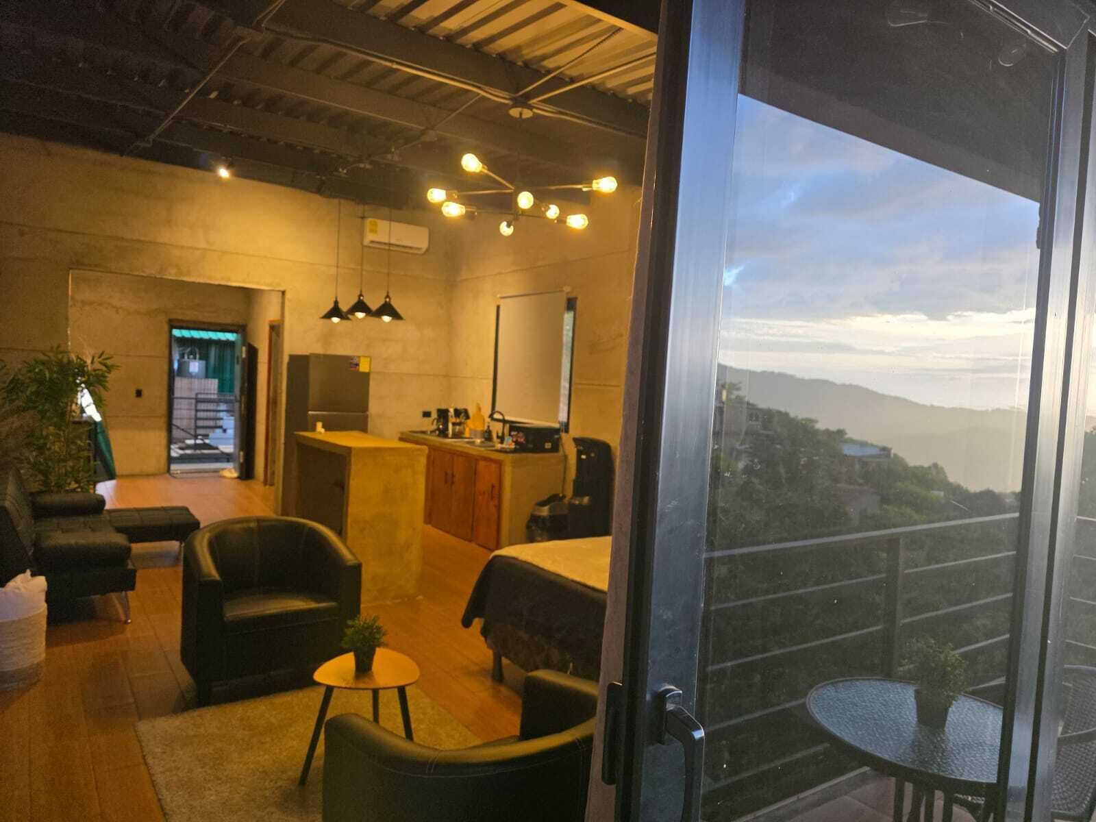 A modern interior with a seating area, a kitchen, and a balcony with a view.
