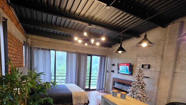 A room with a bed, a small bar area with stools, a television, and a Christmas tree.